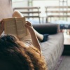 a person lying on a couch reading a book