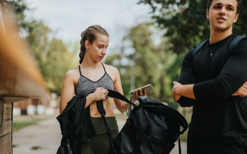 a woman holding a gym bag next to a man